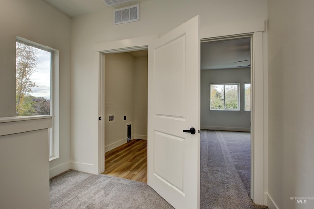 corridor with baseboards, visible vents, and carpet floors