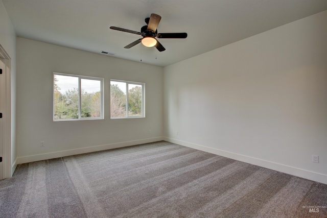 carpeted spare room with baseboards, visible vents, and ceiling fan