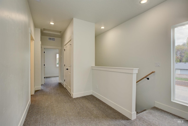 hall with carpet, an upstairs landing, visible vents, and baseboards