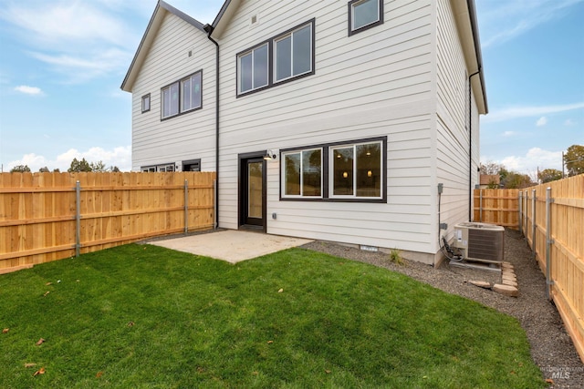 rear view of house with a fenced backyard, a patio area, a lawn, and central AC