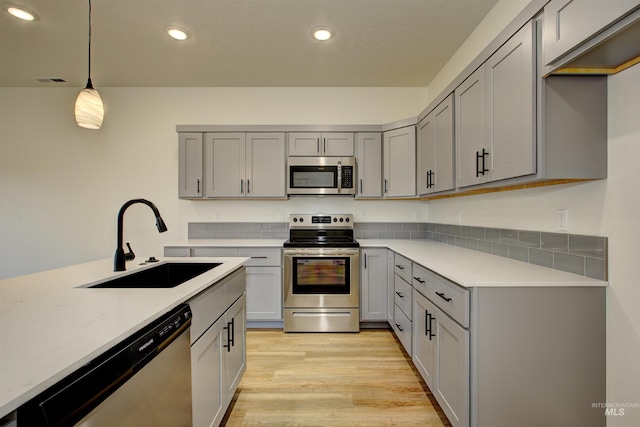 kitchen featuring recessed lighting, a sink, gray cabinetry, stainless steel appliances, and light wood-type flooring