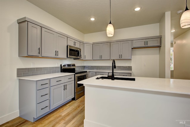 kitchen with light countertops, gray cabinetry, appliances with stainless steel finishes, and a sink