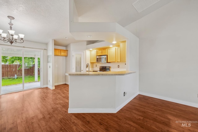 5101 Barkley Way, Caldwell, ID 83607 - kitchen featuring stainless steel appliances, a chandelier, baseboards, wood finished floors, and a peninsula