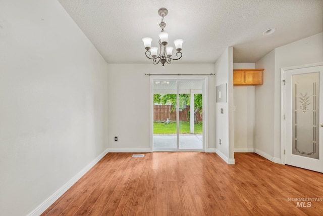 5101 Barkley Way, Caldwell, ID 83607 - unfurnished dining area with a chandelier, light wood finished floors, baseboards, and a textured ceiling