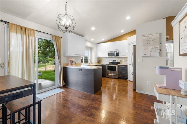 8096 E Jacob, Nampa, ID 83687 - kitchen featuring appliances with stainless steel finishes, a peninsula, vaulted ceiling, white cabinets, and dark wood-type flooring