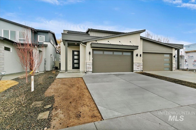 view of front facade with a garage, stone siding, concrete driveway, and stucco siding