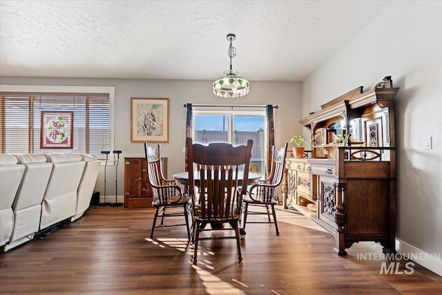 dining room with a notable chandelier, a textured ceiling, dark wood-style floors, a fireplace, and baseboards