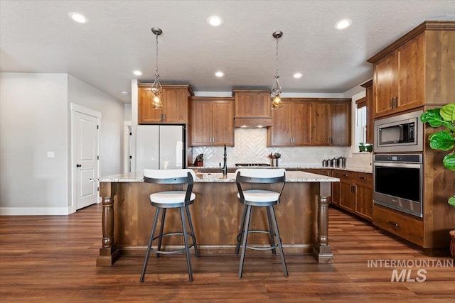 kitchen with dark wood-type flooring, tasteful backsplash, a kitchen island with sink, and stainless steel appliances