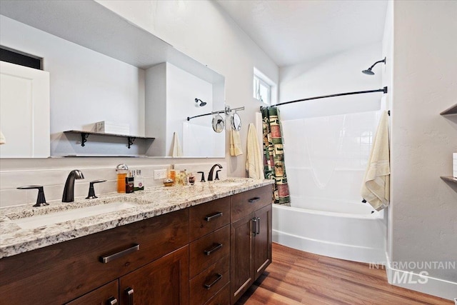 bathroom featuring a sink, wood finished floors, shower / bath combo, and double vanity