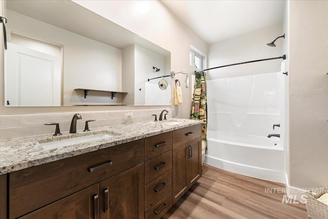 full bath featuring a sink, double vanity, wood finished floors, and shower / tub combo