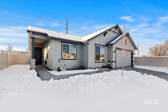 view of front facade featuring board and batten siding, an attached garage, and fence