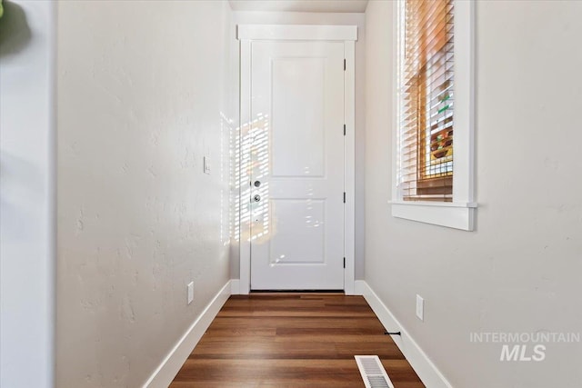 doorway featuring visible vents, baseboards, and dark wood-style flooring