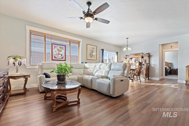 living area featuring baseboards, a textured ceiling, and wood finished floors