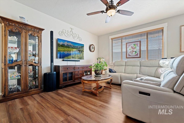 living room featuring ceiling fan, a textured ceiling, and wood finished floors