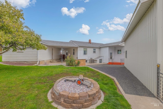 back of property with a patio, a lawn, and a fire pit