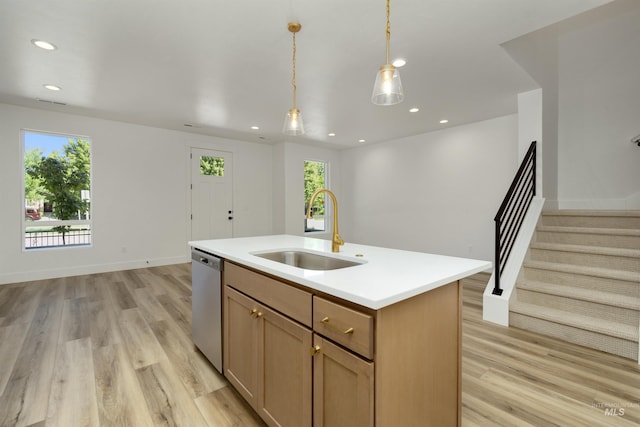 kitchen featuring sink, hanging light fixtures, a kitchen island with sink, stainless steel dishwasher, and light hardwood / wood-style flooring