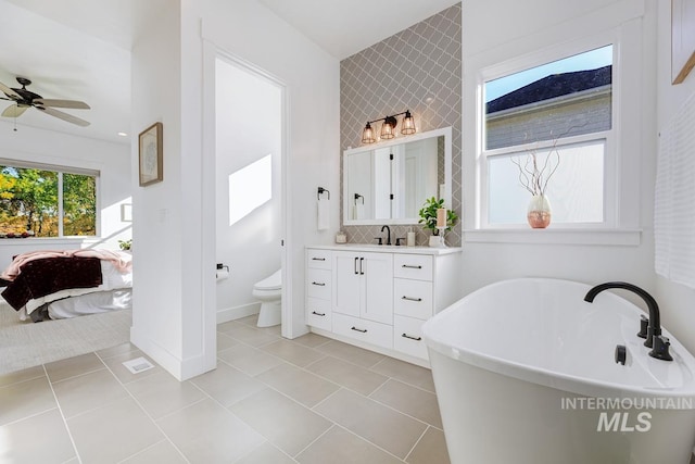 full bath with toilet, vanity, decorative backsplash, a freestanding tub, and ensuite bath