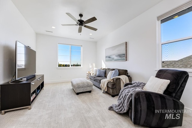 living room with plenty of natural light, light colored carpet, baseboards, and ceiling fan