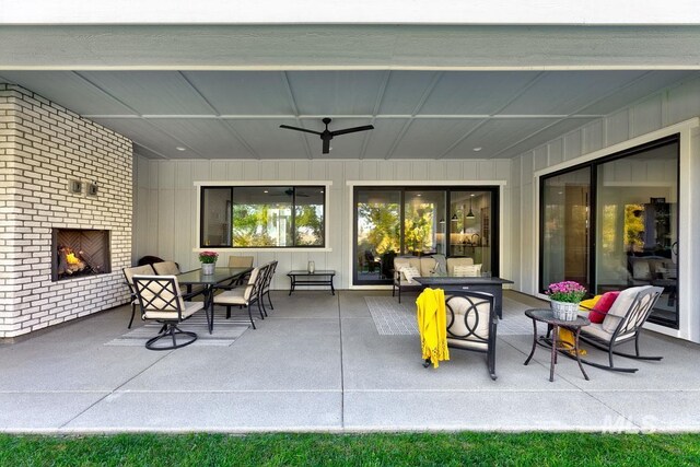 view of patio featuring outdoor dining space, an outdoor brick fireplace, and ceiling fan