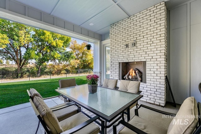 view of patio / terrace with fence, outdoor dining space, and an outdoor brick fireplace