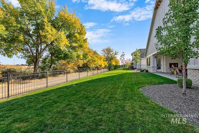 view of yard with a patio area, exterior fireplace, and a fenced backyard