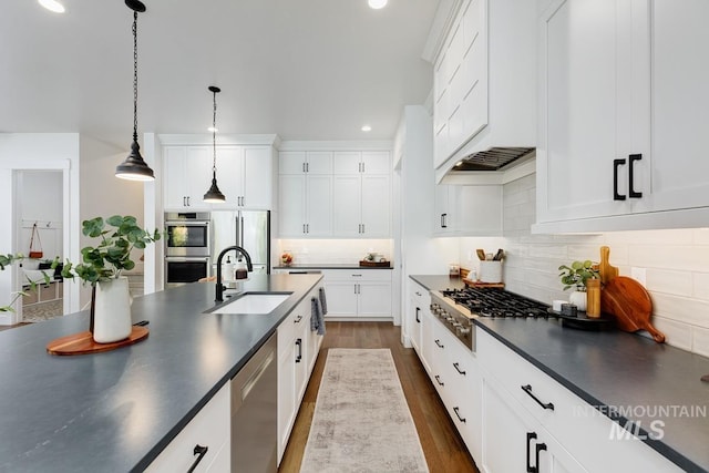 kitchen featuring dark countertops, dark wood finished floors, stainless steel appliances, and a sink