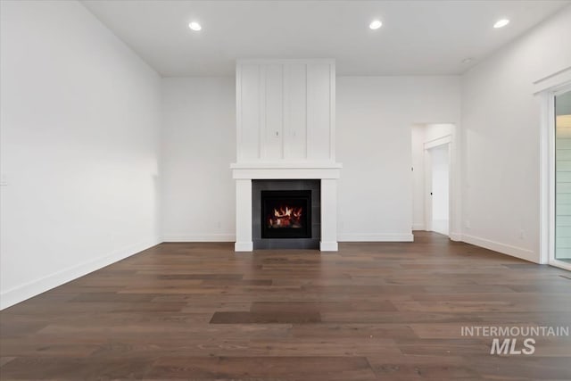 unfurnished living room featuring dark wood-type flooring and a tile fireplace