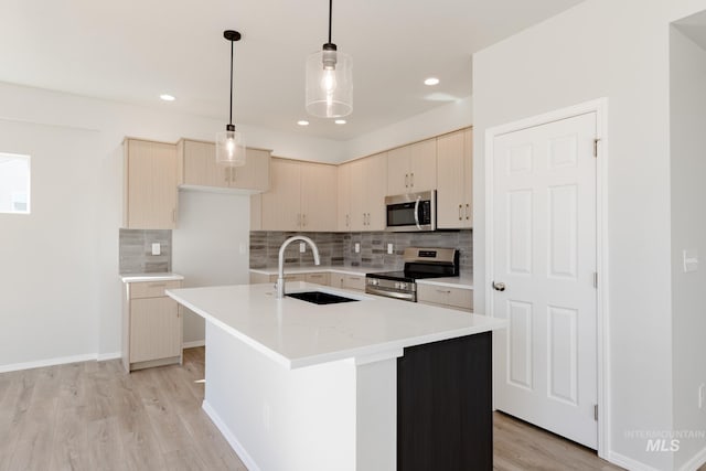 kitchen featuring light brown cabinetry, sink, appliances with stainless steel finishes, an island with sink, and pendant lighting