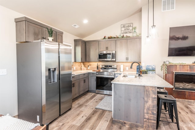 kitchen featuring a breakfast bar, sink, hanging light fixtures, tasteful backsplash, and stainless steel appliances