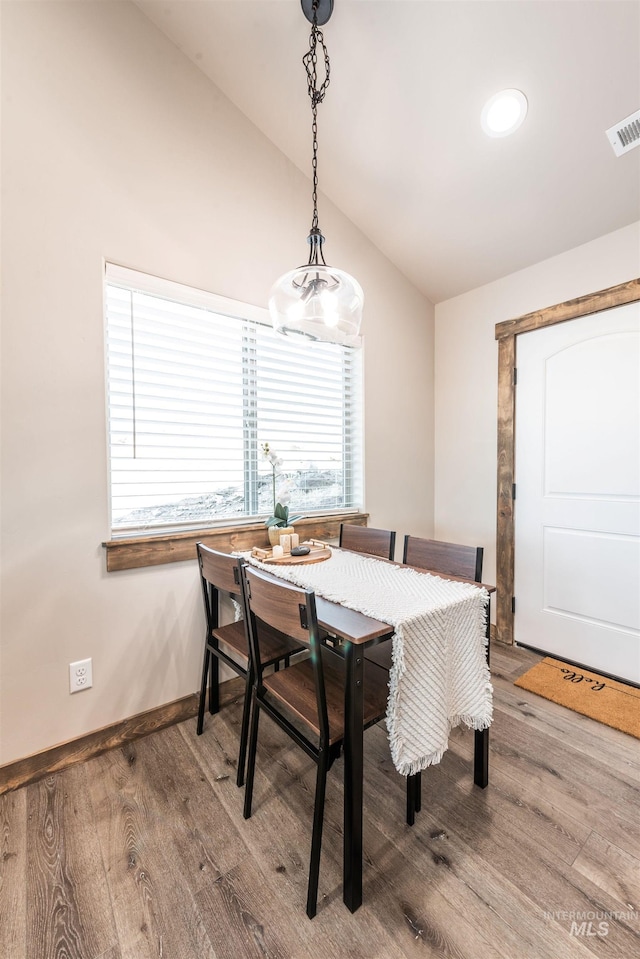 dining room with hardwood / wood-style flooring and vaulted ceiling