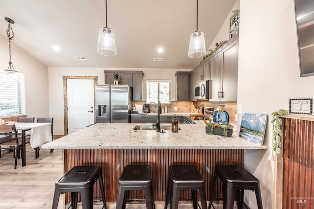 kitchen featuring sink, hanging light fixtures, backsplash, kitchen peninsula, and appliances with stainless steel finishes