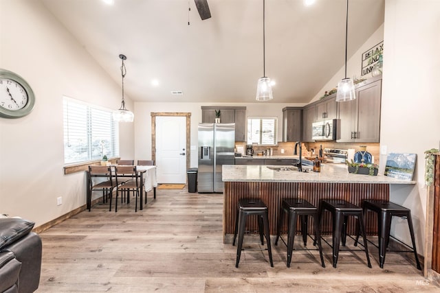 kitchen featuring a kitchen breakfast bar, sink, decorative backsplash, kitchen peninsula, and stainless steel appliances