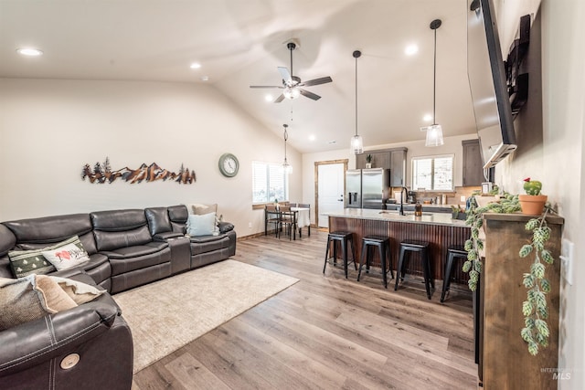 living room featuring a wealth of natural light, ceiling fan, vaulted ceiling, and light wood-type flooring