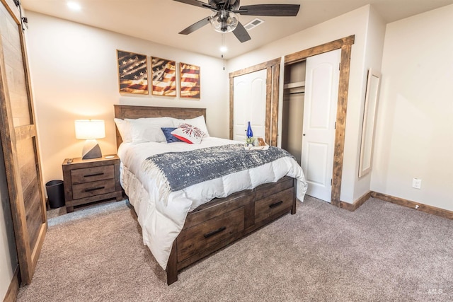 carpeted bedroom featuring a barn door and ceiling fan