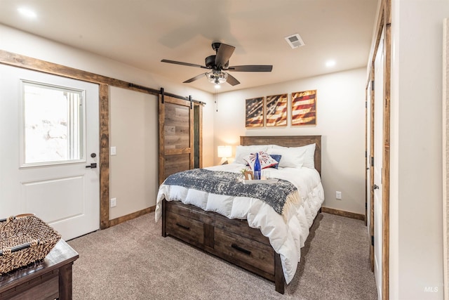 carpeted bedroom featuring ceiling fan and a barn door