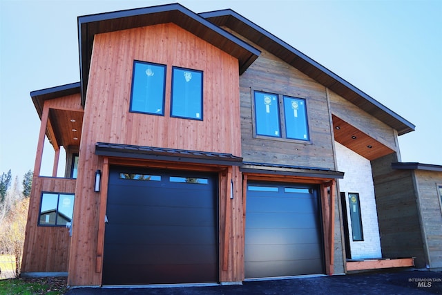 contemporary house featuring a garage, a standing seam roof, and metal roof