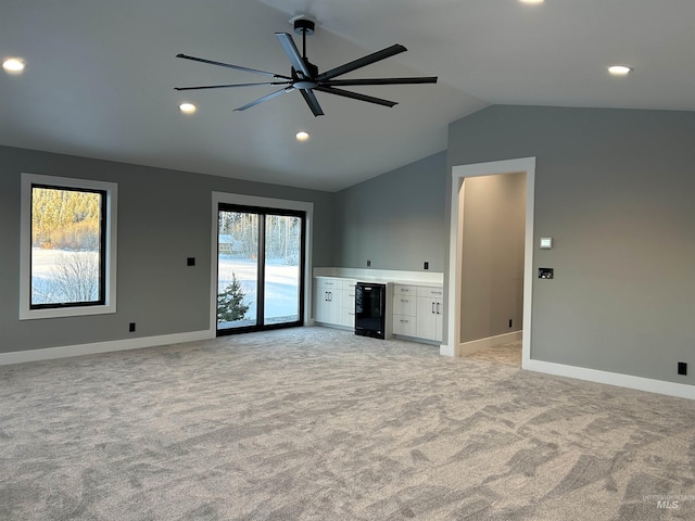 unfurnished living room featuring light carpet, recessed lighting, baseboards, lofted ceiling, and wine cooler