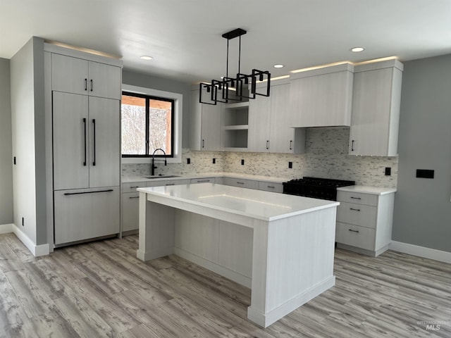 kitchen with light countertops, hanging light fixtures, a sink, and a center island