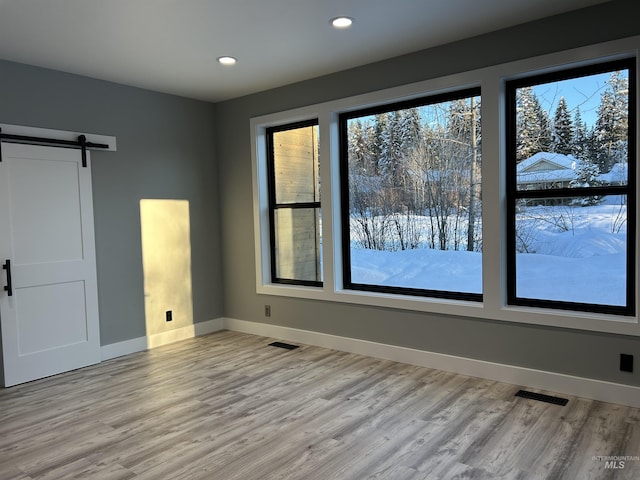 empty room featuring baseboards, plenty of natural light, a barn door, and visible vents