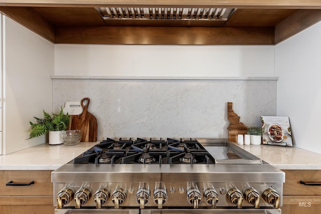 details with tasteful backsplash, gas range, and light countertops