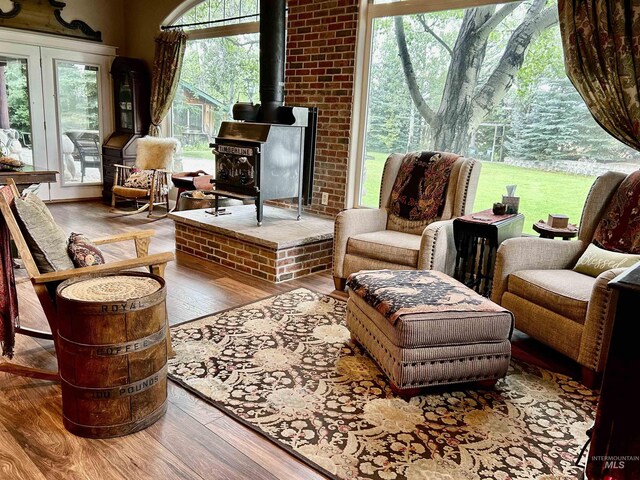 sitting room featuring brick wall, light hardwood / wood-style floors, and a wood stove