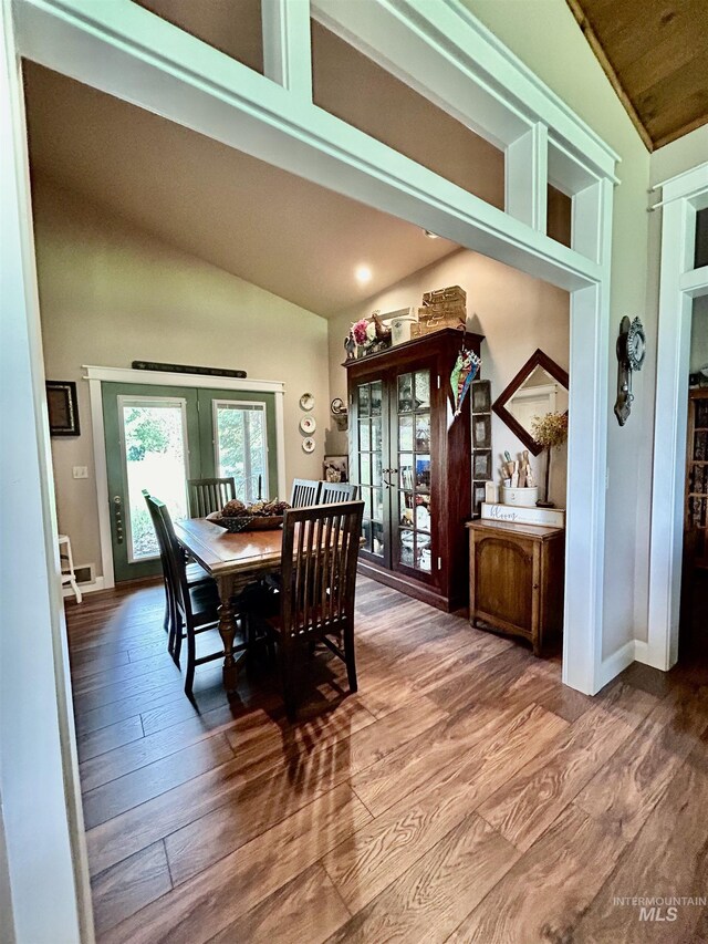 dining space featuring wood-type flooring, lofted ceiling, and french doors