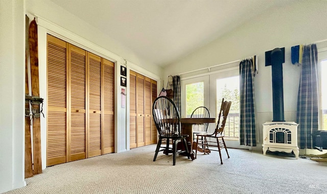 dining space featuring a wood stove, carpet flooring, and lofted ceiling