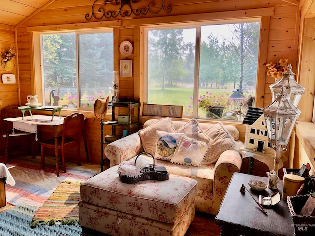 living room featuring wood walls, lofted ceiling, and a healthy amount of sunlight