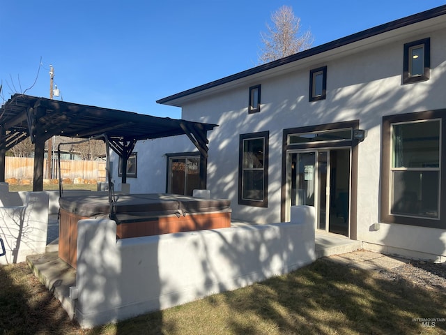 rear view of house with a pergola and a covered hot tub