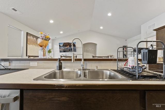 kitchen featuring dark brown cabinetry, sink, and vaulted ceiling