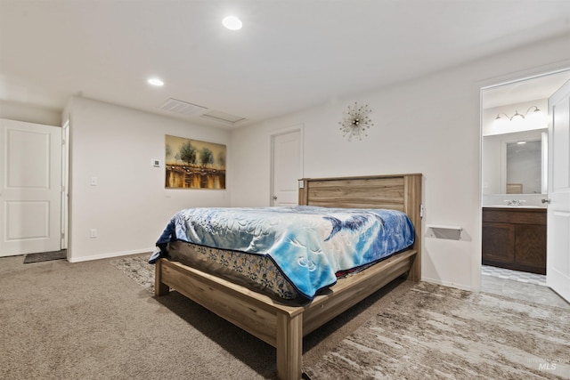 bedroom with ensuite bath, light carpet, and sink