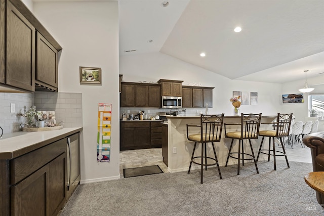 kitchen with a kitchen bar, decorative backsplash, light colored carpet, and dark brown cabinets