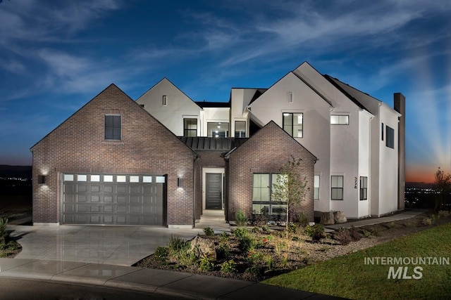 view of front of property featuring a garage, brick siding, concrete driveway, and stucco siding