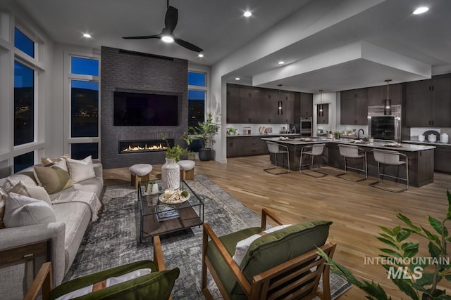 living room featuring recessed lighting, a brick fireplace, light wood-type flooring, and ceiling fan